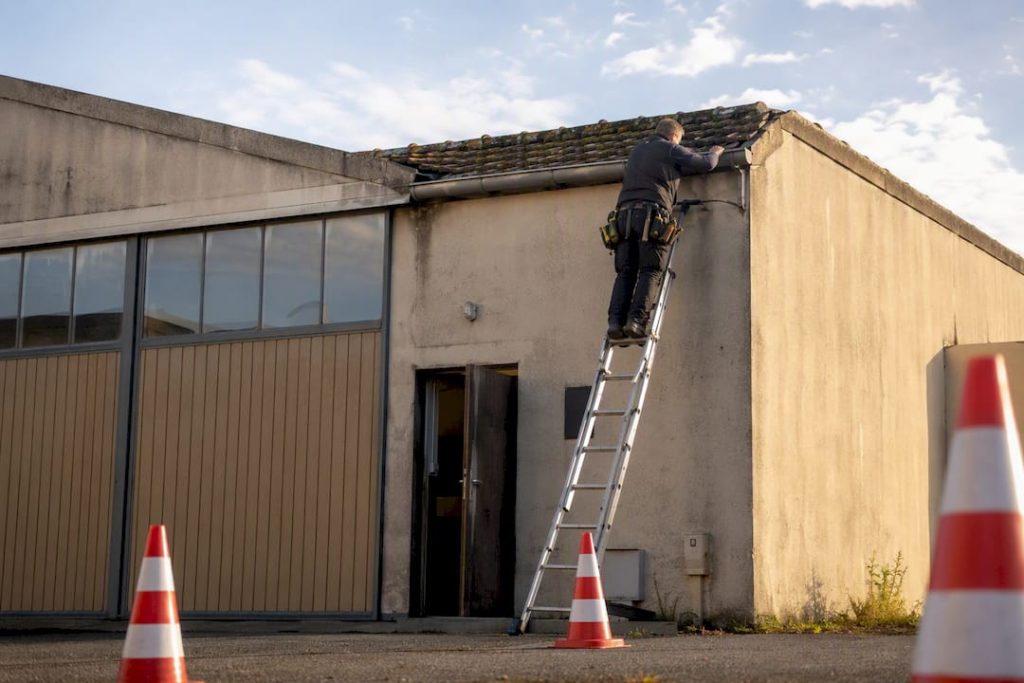 Monteur voert dakreparatie uit aan bedrijfspand