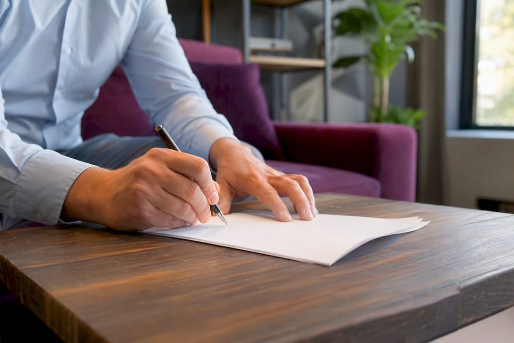 Handen die een transportakte met een pen ondertekenen