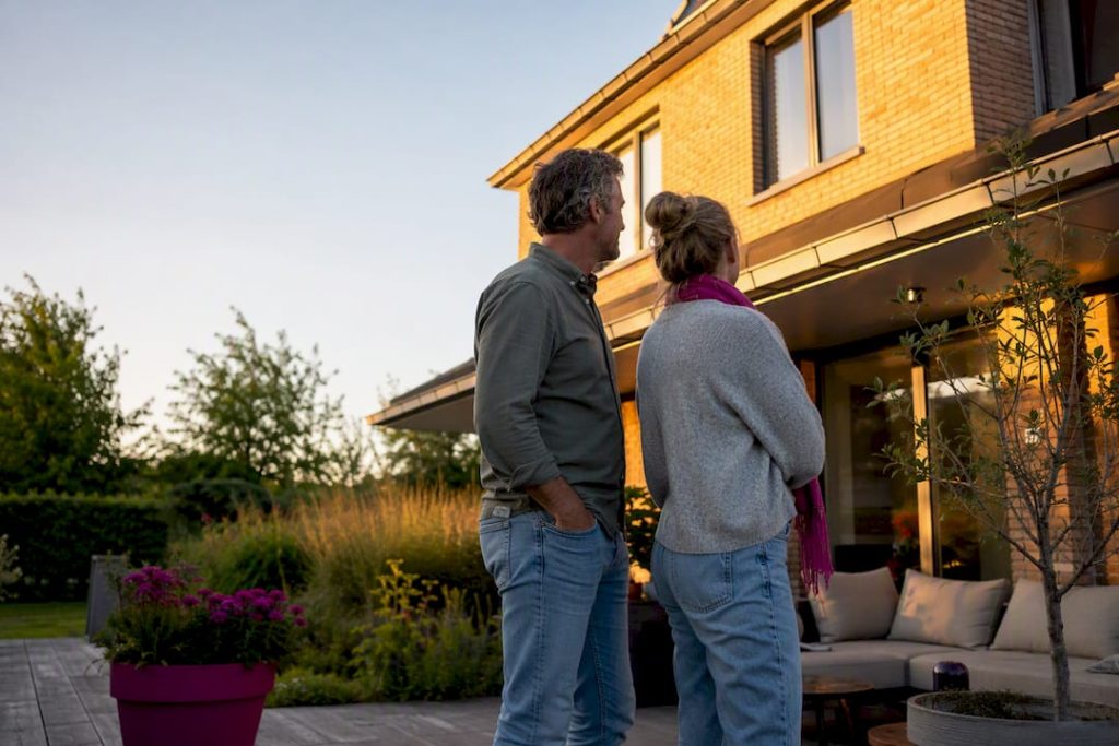 Huiseigenaren bekijken hun huis vanaf het terras