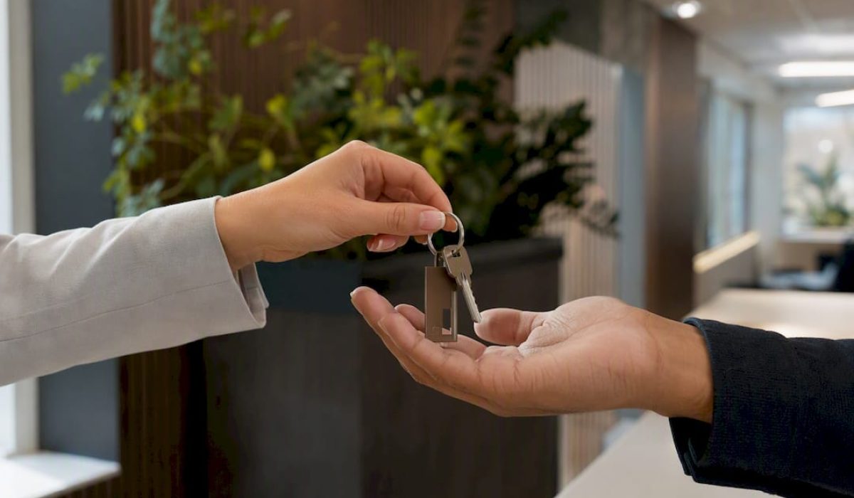 Twee handen die een huissleutel met sleutelhanger aan elkaar overdragen.